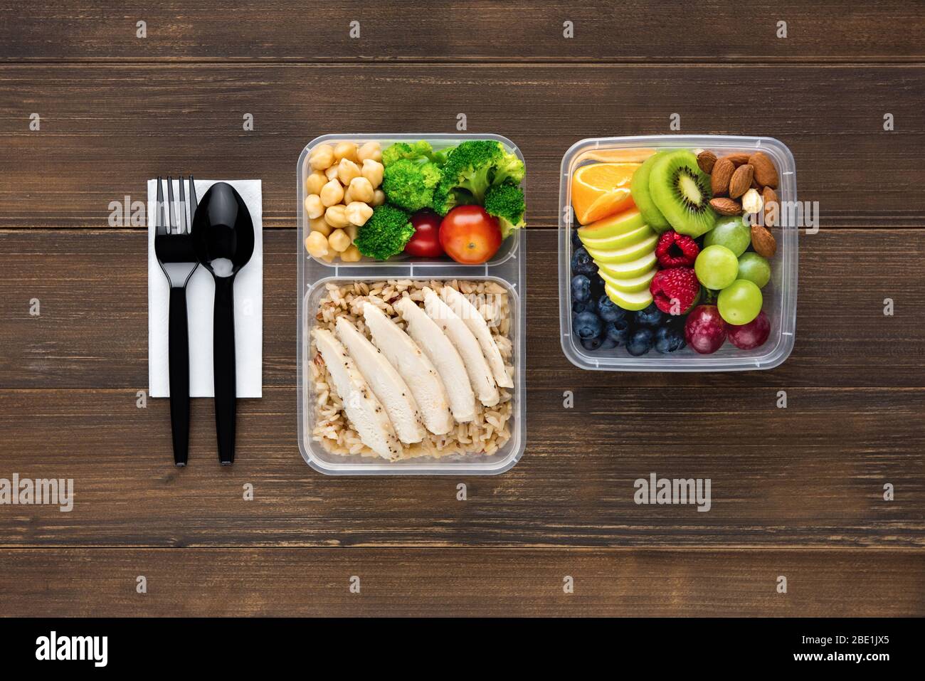 Draufsicht der gesunden nährstoffreichen Lebensmittel in Take Away Boxen mit Löffel und Gabel auf Holztisch bereit zu essen gesetzt Stockfoto