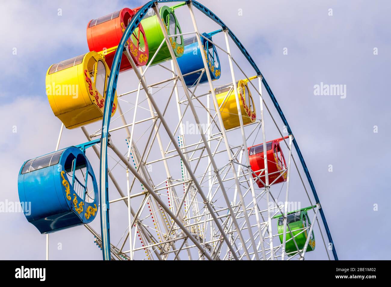 Riesenrad mit bunten Kabinen gegen den Himmel mit Wolken im Park an einem sonnigen Frühlingstag. Stockfoto