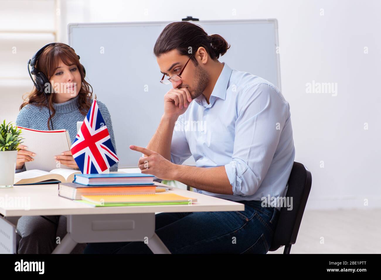 Junger Schüler und männlicher englischlehrer im Klassenzimmer Stockfoto