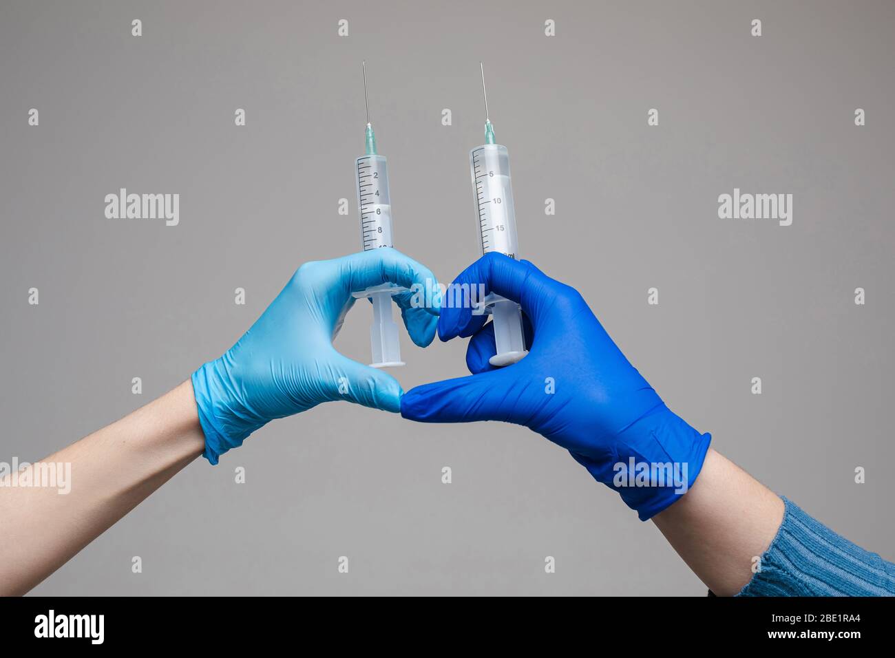 Zwei Hände in Handschuhen halten Spritzen Studio Schuss. Stockfoto