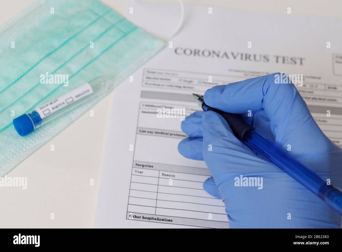 Laborversuch zur Bestimmung des Coronavirus. Konzept. Der Patient füllt die Einwilligungserklärung zur Analyse aus. Das Reagenzglas sagt POSITIV und NEGATIV Stockfoto
