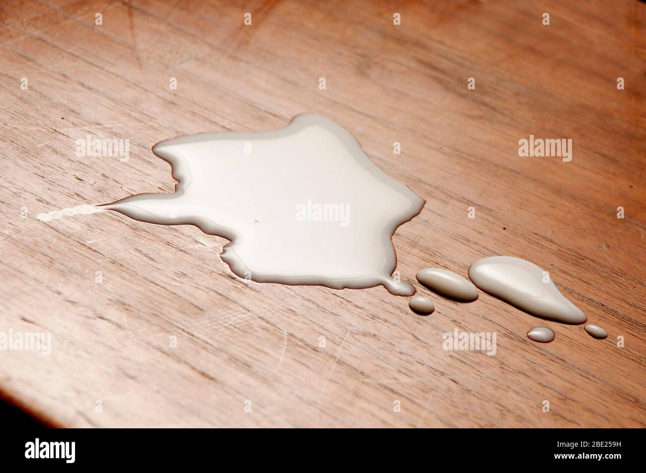 Verschüttete Milch oder verschüttete Milchtropfen auf einer Tischplatte Stockfoto