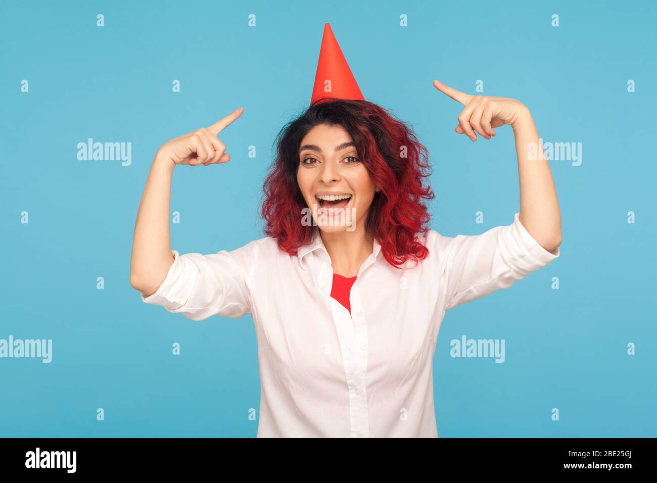 Porträt von aufgeregt glücklich begeisterten Hipster Mädchen zeigt auf lustige Party-Kegel auf dem Kopf, feiern Erfolg, persönliches Wachstum, Jubiläum und holida Stockfoto