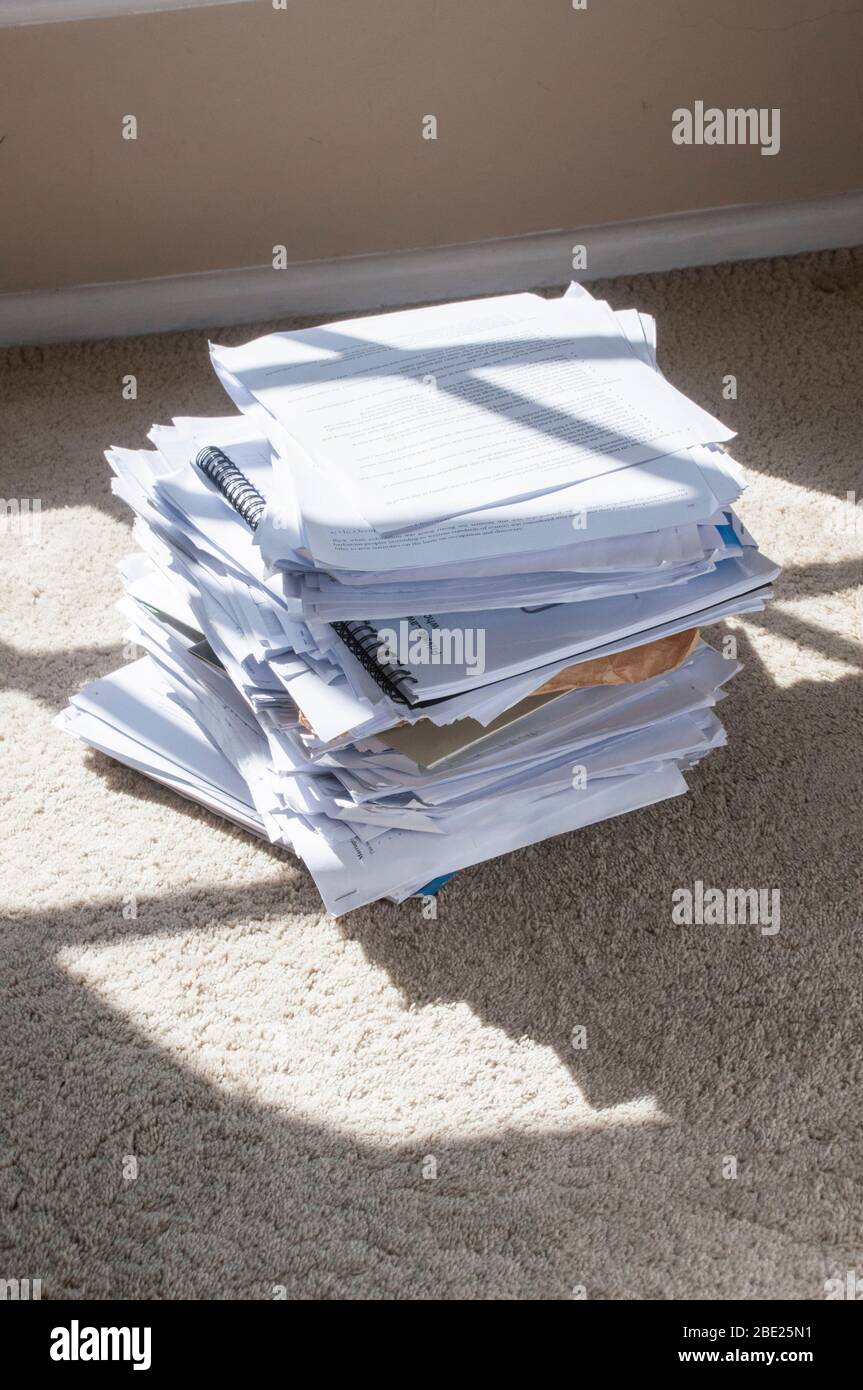 Unordentlich Stapel Dokument Papiere auf einem Teppich in etwas Sonnenlicht Stockfoto