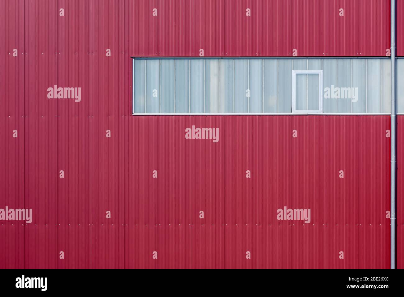 Moderne Fabrikfassade mit roten Elementen und einem Lichtband verkleidet Stockfoto