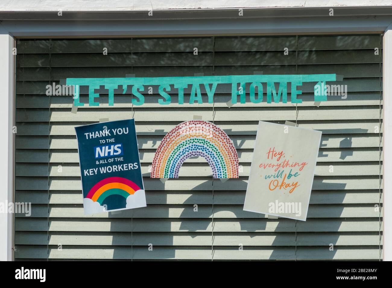 10. April 2020. Während der Aussperrung des Coronavirus Covid-19 im Jahr 2020 wurde der Regenbogen zum Symbol der Unterstützung für Menschen, die Solidarität mit den Beschäftigten des Gesundheitsdienstes an der Front zeigen wollen. Dieses Haus hat ein Regenbogenbild, ein Plakat, das den Mitarbeitern des NHS und allen Schlüsselarbeitern Danke sagt, eine Nachricht Lass uns zu Hause bleiben und eine positive hoffnungsvolle Botschaft, dass alles in Ordnung sein wird, in einem Fenster angezeigt. Stockfoto