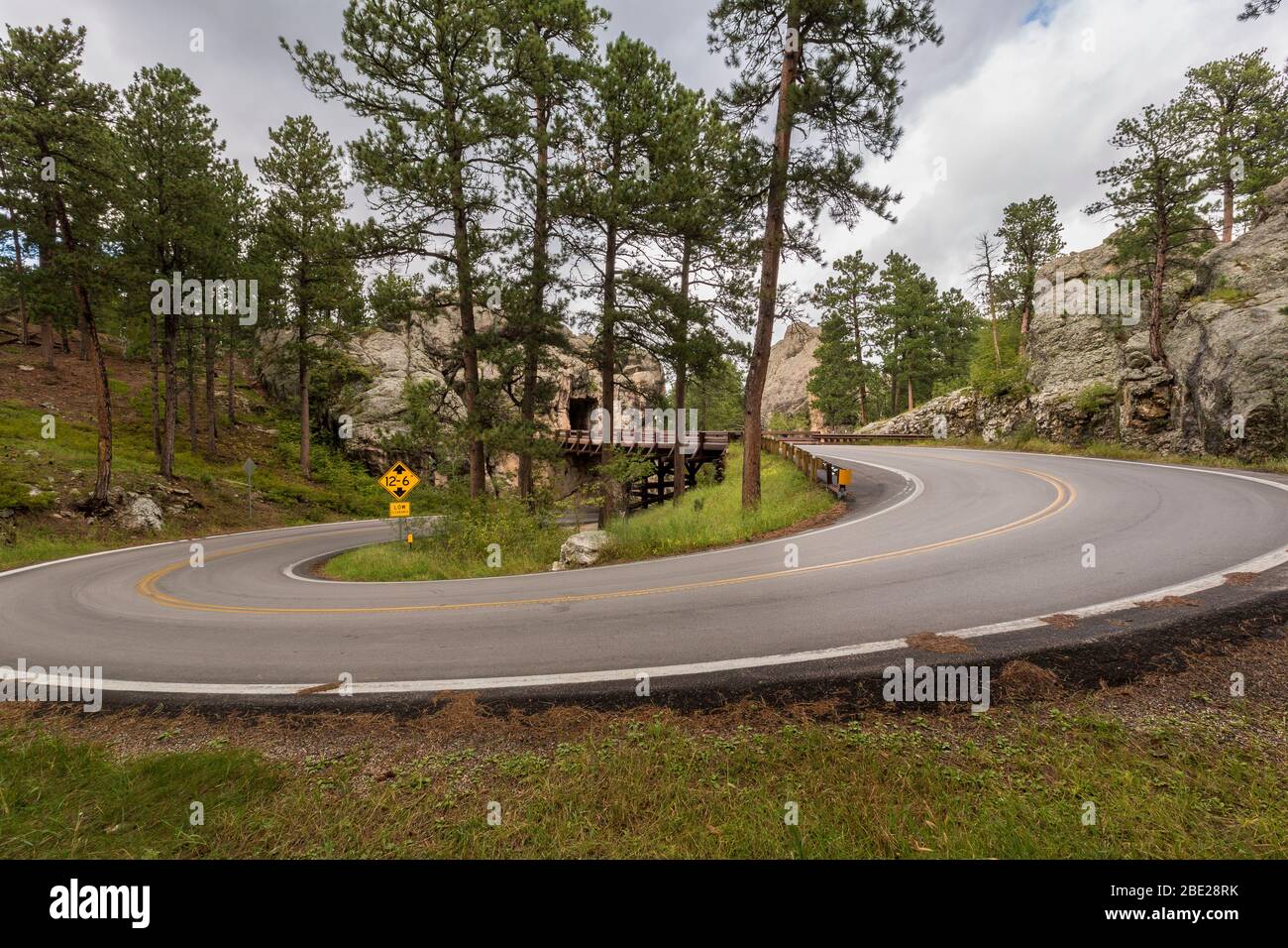 Eine Straße mit einer über- und Unterbrücke mit einem Tunnel durch einen Felsen. Stockfoto
