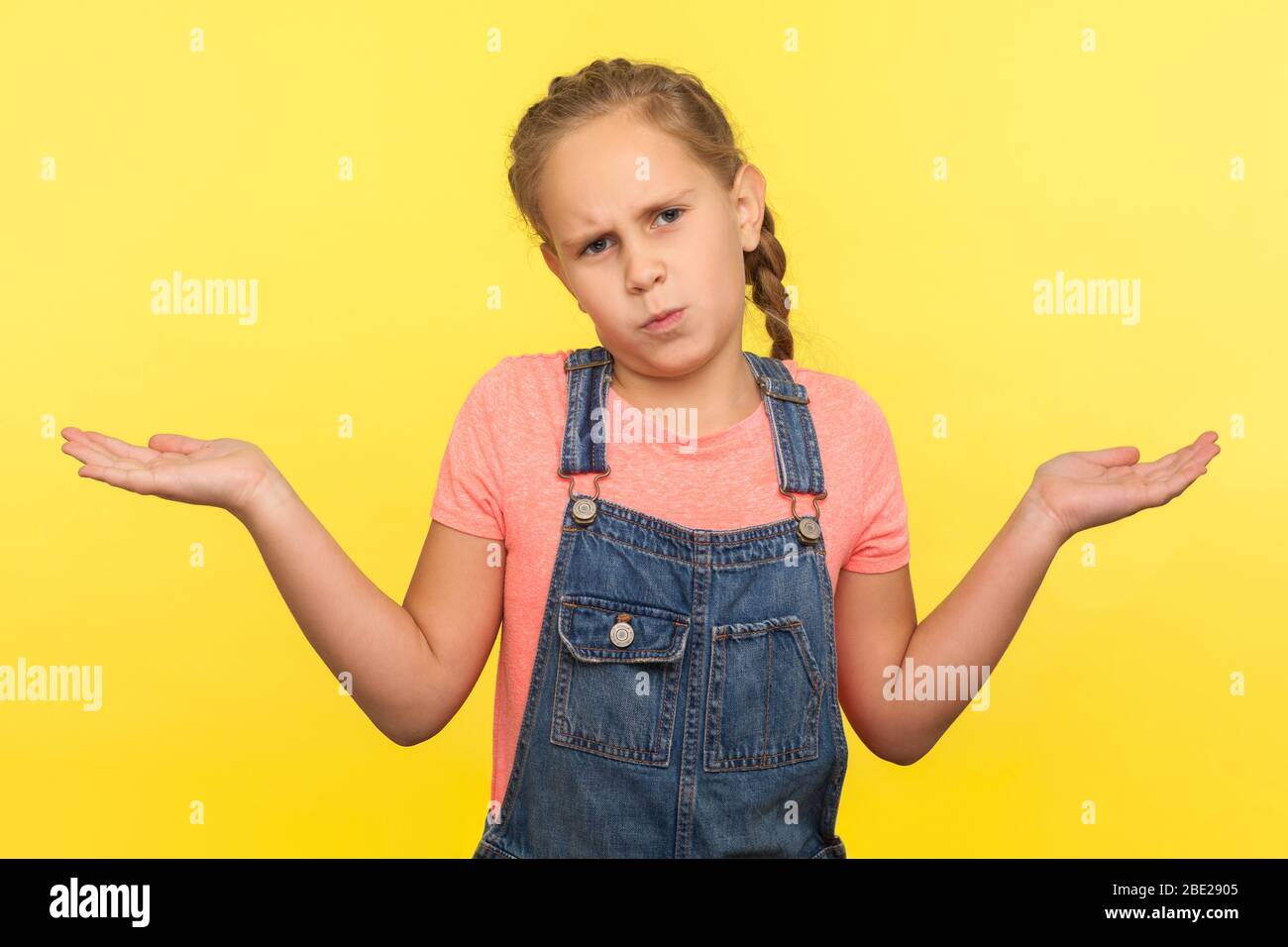 Ich weiß es nicht! Porträt des ahnungslosen ungewissen kleinen Mädchen in Denim Overalls Hände heben in Fragebewegung, unsicher der Antwort, Ausdruck von Zweifeln. Stockfoto