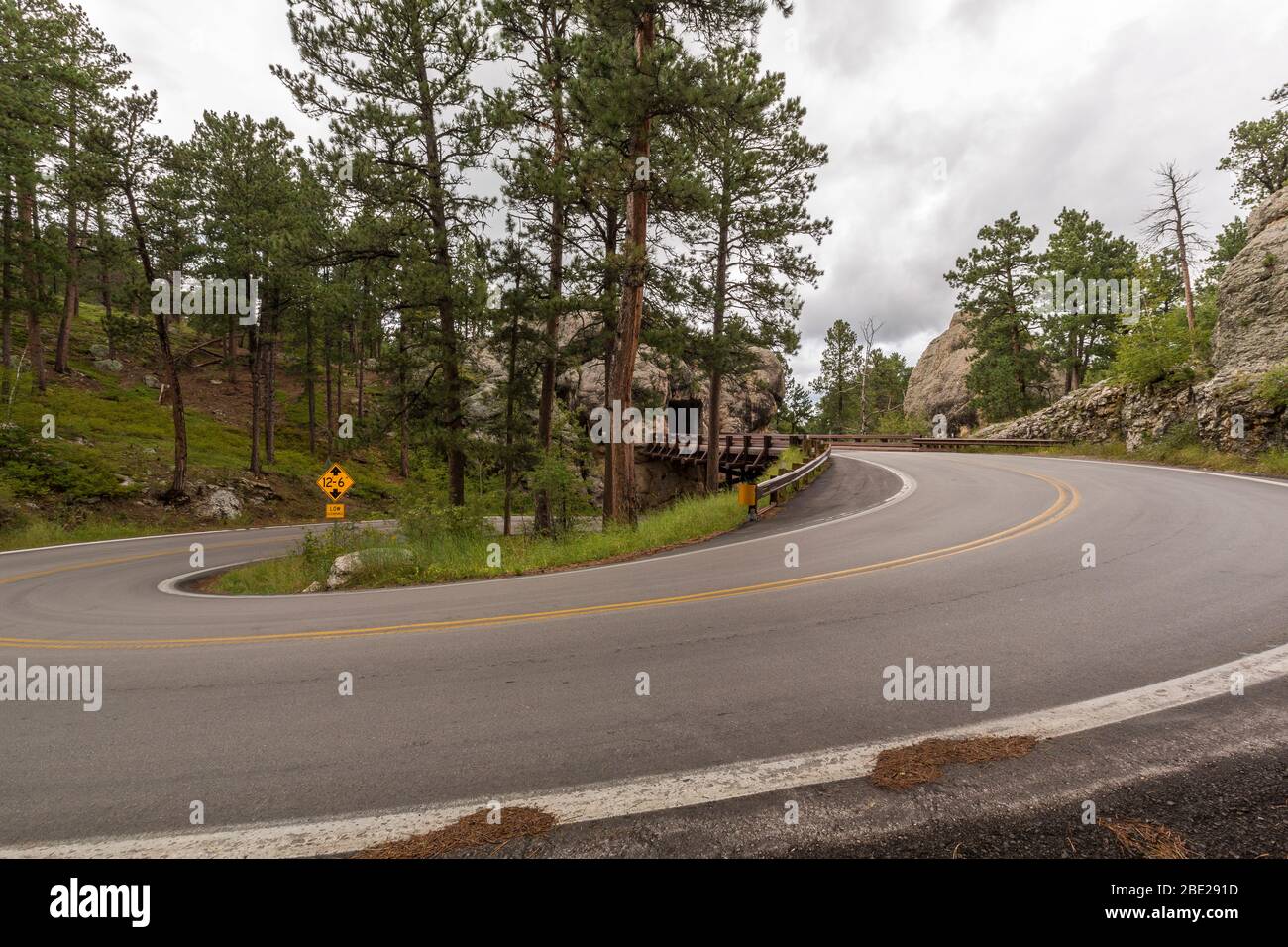 Eine Straße mit einer über- und Unterbrücke mit einem Tunnel durch einen Felsen. Stockfoto