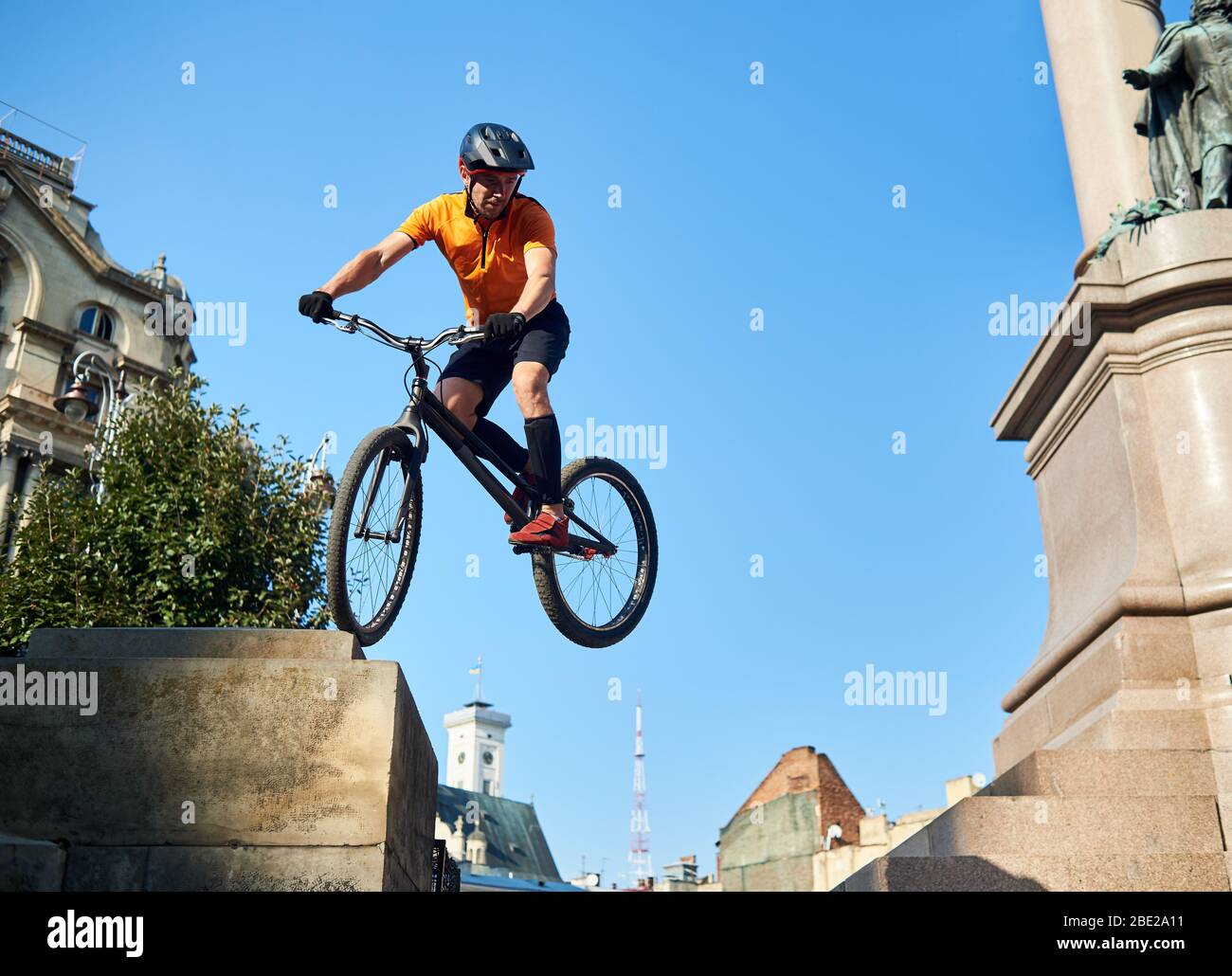 Junge Radfahrer Durchführung gefährlicher Sprünge auf dem Mountainbike auf der Treppe des Denkmals Sockel über blauen Himmel, Konzept des Extremsports Stockfoto
