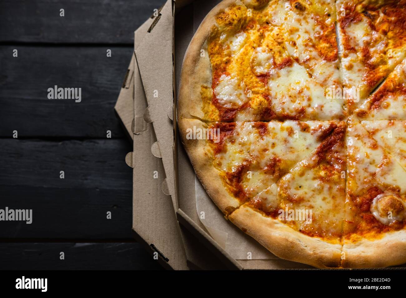 Kalte Pizza in einer Lieferbox, lange Lieferzeiten, verschwendete Fast-Food-Konzept. Italienische Pizza margherita mit trockener Kruste und Sauce, verzögertes oder fehlgeschlagenes Essen Stockfoto