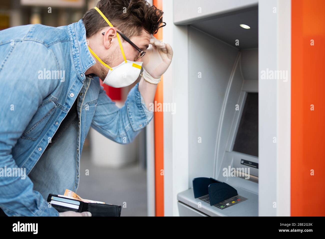 Mann entsetzt über einen Geldautomaten, finanzielle Not während der Zeit der Korona-Krise Stockfoto