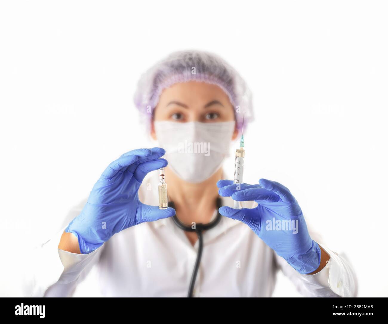 Weibliche Ärztin in medizinischen Schutzmaske und Handschuhe zeigt Impfstoff Ampulle. Prävention und Stop Infektion Konzept. Coronavirus stoppen. Stockfoto