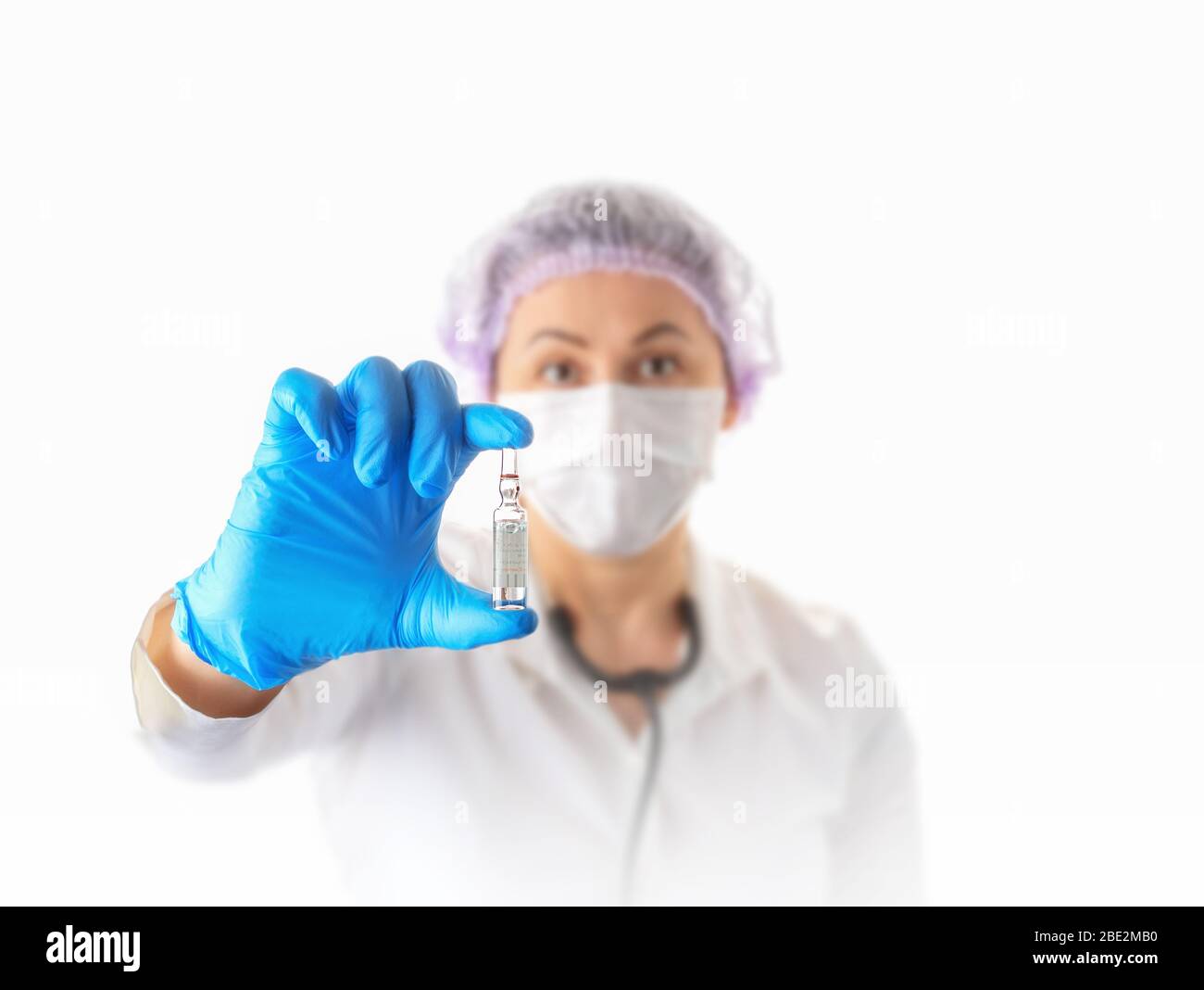 Weibliche Ärztin in medizinischen Schutzmaske und Handschuhe zeigt Impfstoff Ampulle. Prävention und Stop Infektion Konzept. Coronavirus stoppen. Konzentrieren Sie sich auf die Hand. Stockfoto