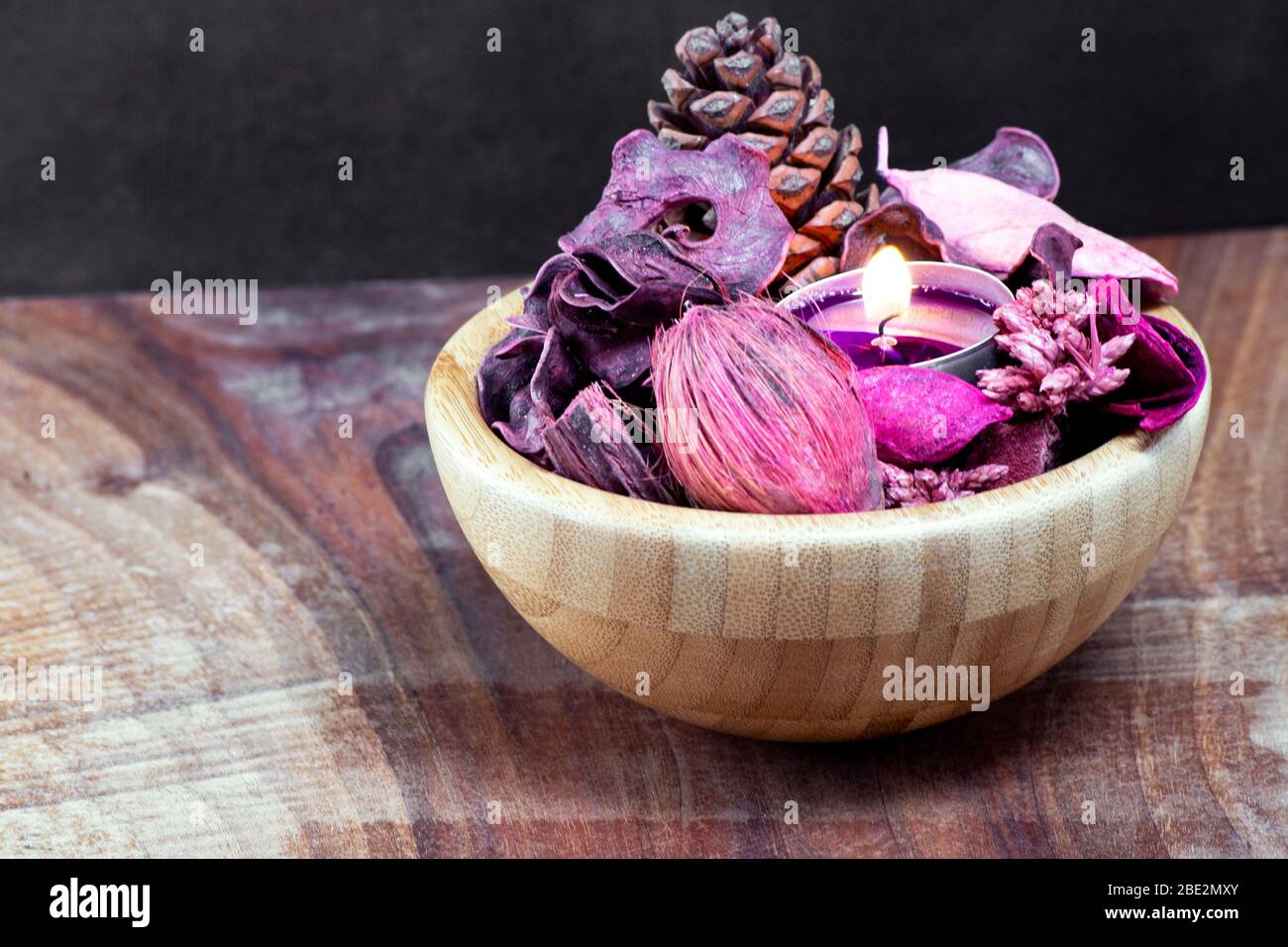 Pourple Teelicht und trocken Potpourri in einer Holzschale über einem Tisch mit schwarzem Hintergrund Stockfoto