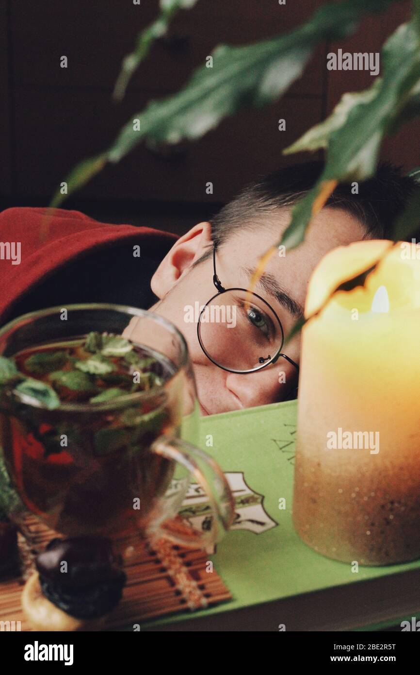 Glück. Dunkle mystische und ruhige Stimmung. Buch und heißen Tee mit Minze und Honig auf dem Tisch mit grünen Pflanzen. Frühlingsmorgen zu Hause. Gesundes Getränk. Bildung Stockfoto