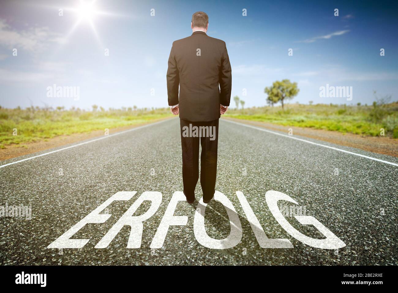 Ein Geschaeftsmann auf einer einsamen Straße, auf der 'Erfolg' steht Stockfoto