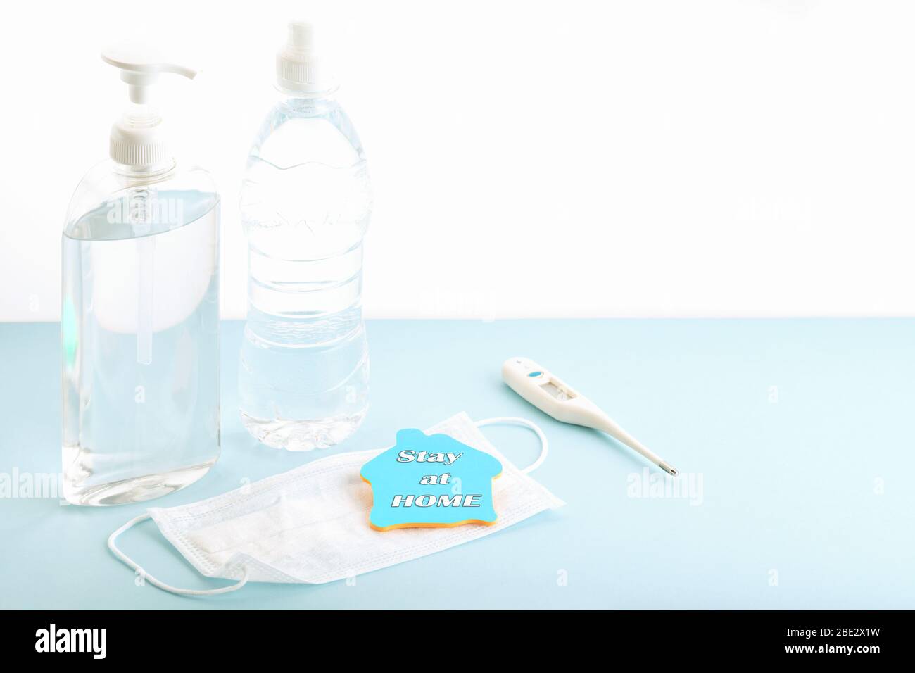 Coronavirus Prävention medizinische chirurgische Maske, Thermometer, Flasche Wasser und Hand Desinfektionsmittel Gel für die Handhygiene Corona Virenschutz. Bleib zu Hause Stockfoto