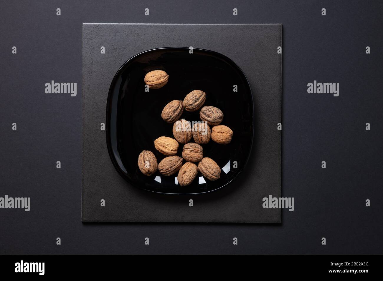 Ein fantastisches Stillleben-Studiobild von Wallnuts auf einer schwarzen Platte auf schwarzem dunklen Hintergrund, topview Stockfoto