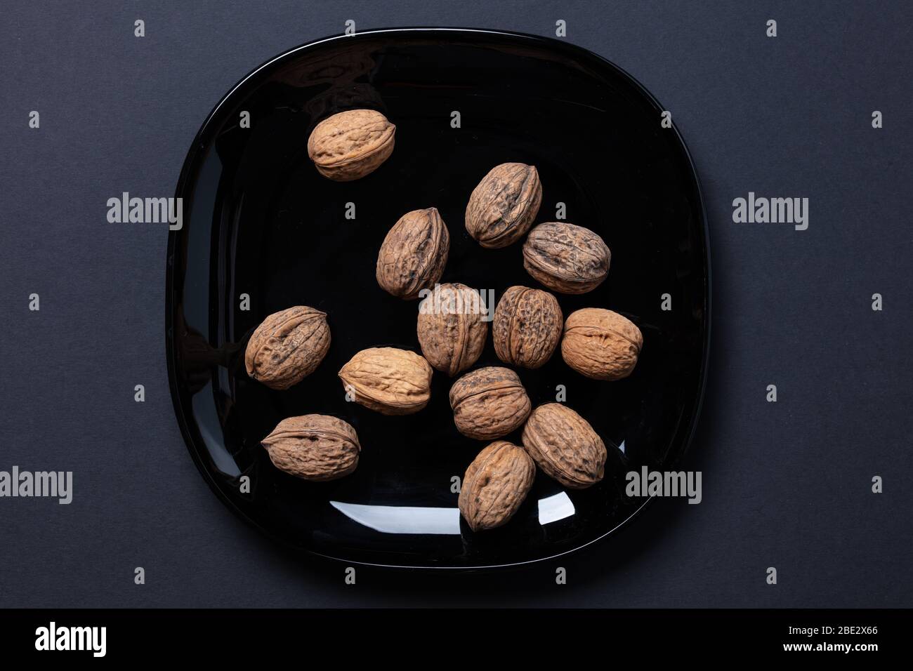 Ein fantastisches Stillleben-Studiobild von Wallnuts auf einer schwarzen Platte auf schwarzem dunklen Hintergrund, topview Stockfoto