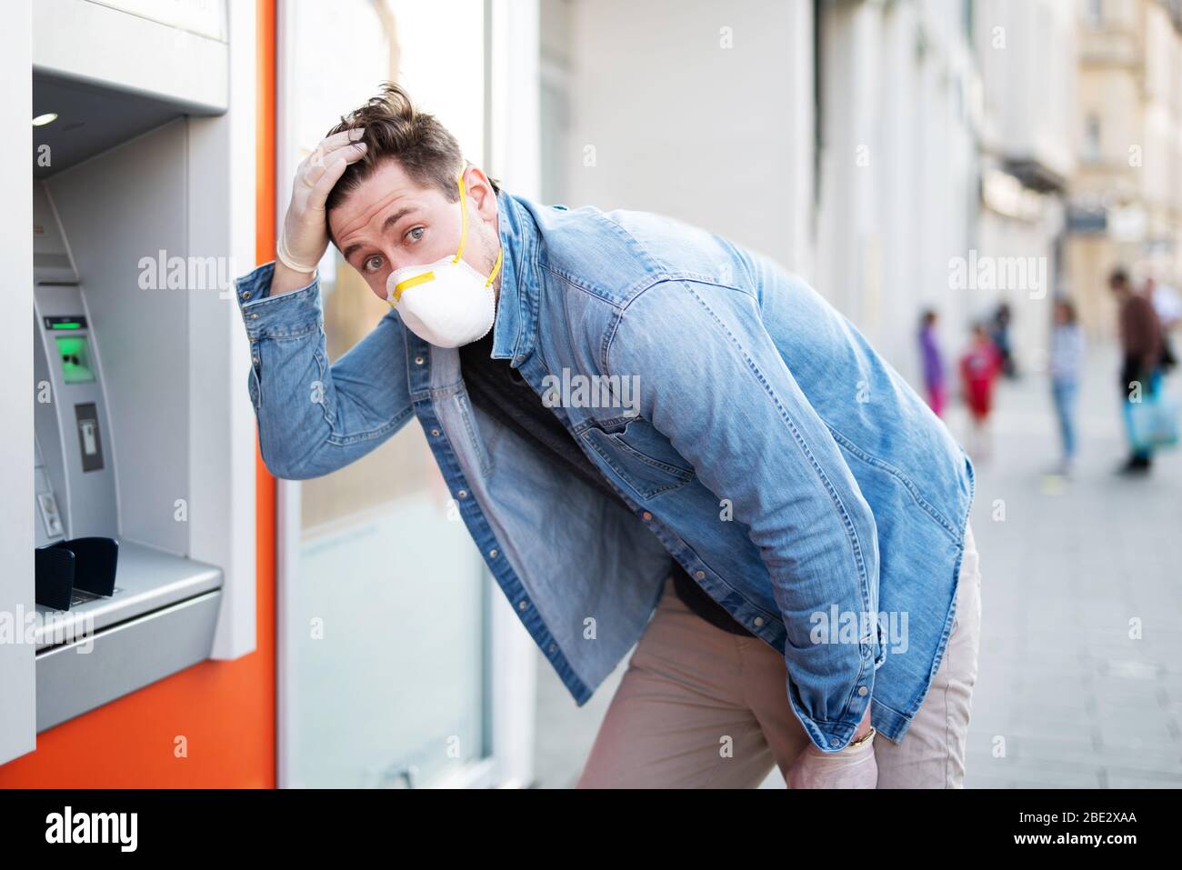 Mann entsetzt über einen Geldautomaten, finanzielle Not während der Zeit der Korona-Krise Stockfoto