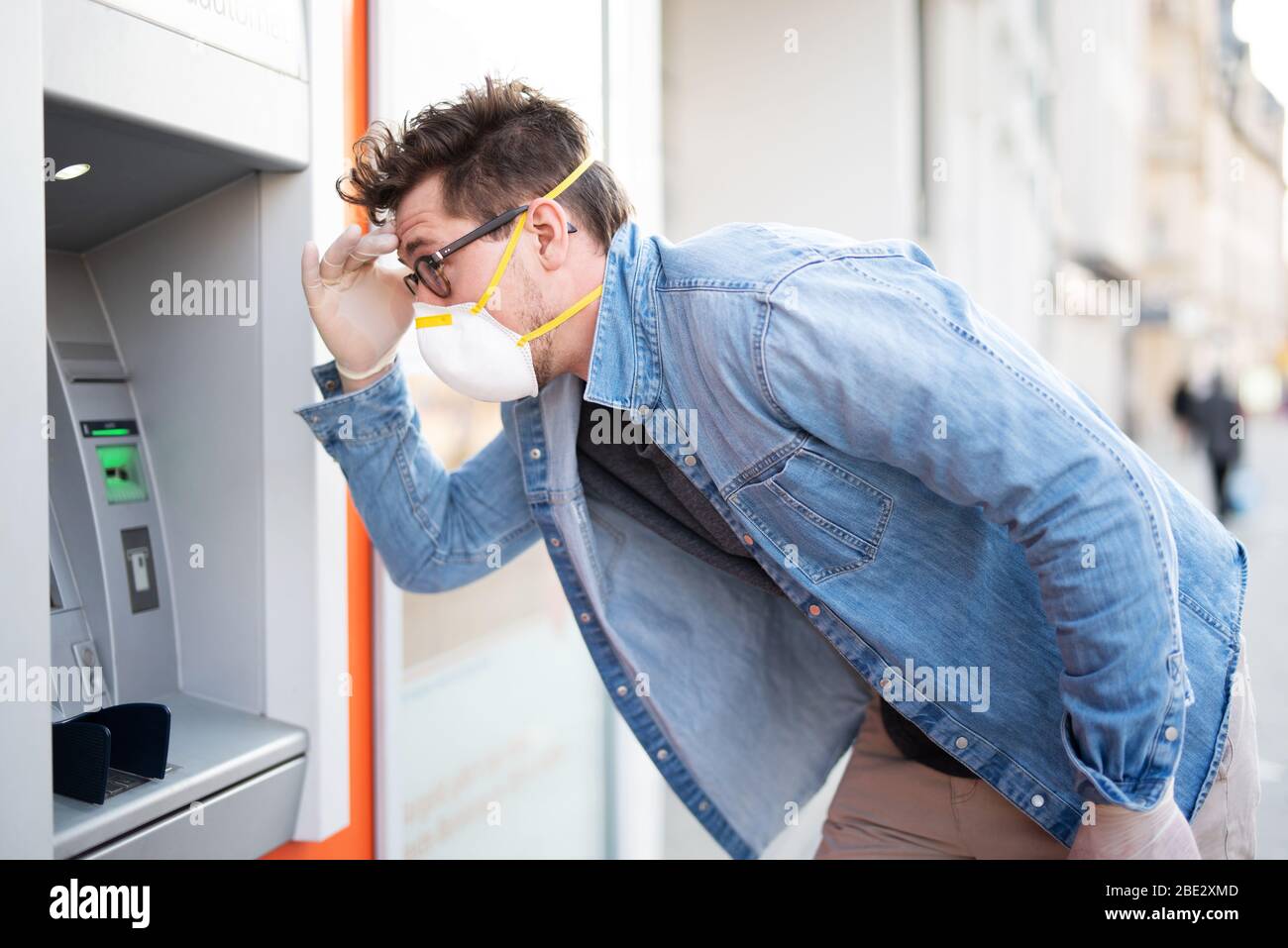 Mann entsetzt über einen Geldautomaten, finanzielle Not während der Zeit der Korona-Krise Stockfoto