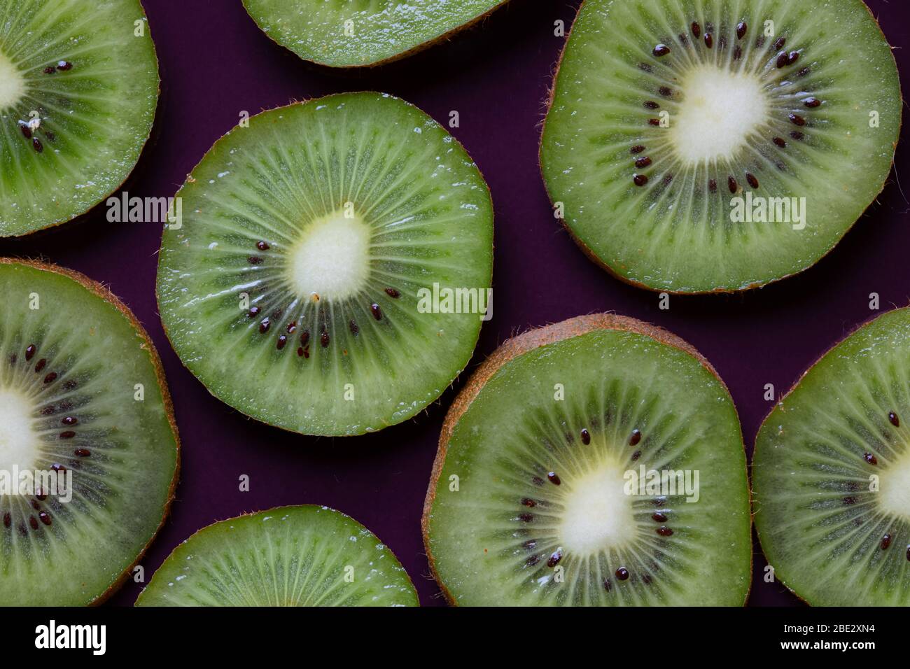 topview ist eine fantastische Fotokomposition aus frischen, leckeren, geschnittenen Kiwi-Früchten auf einem violetten Hintergrund Stockfoto