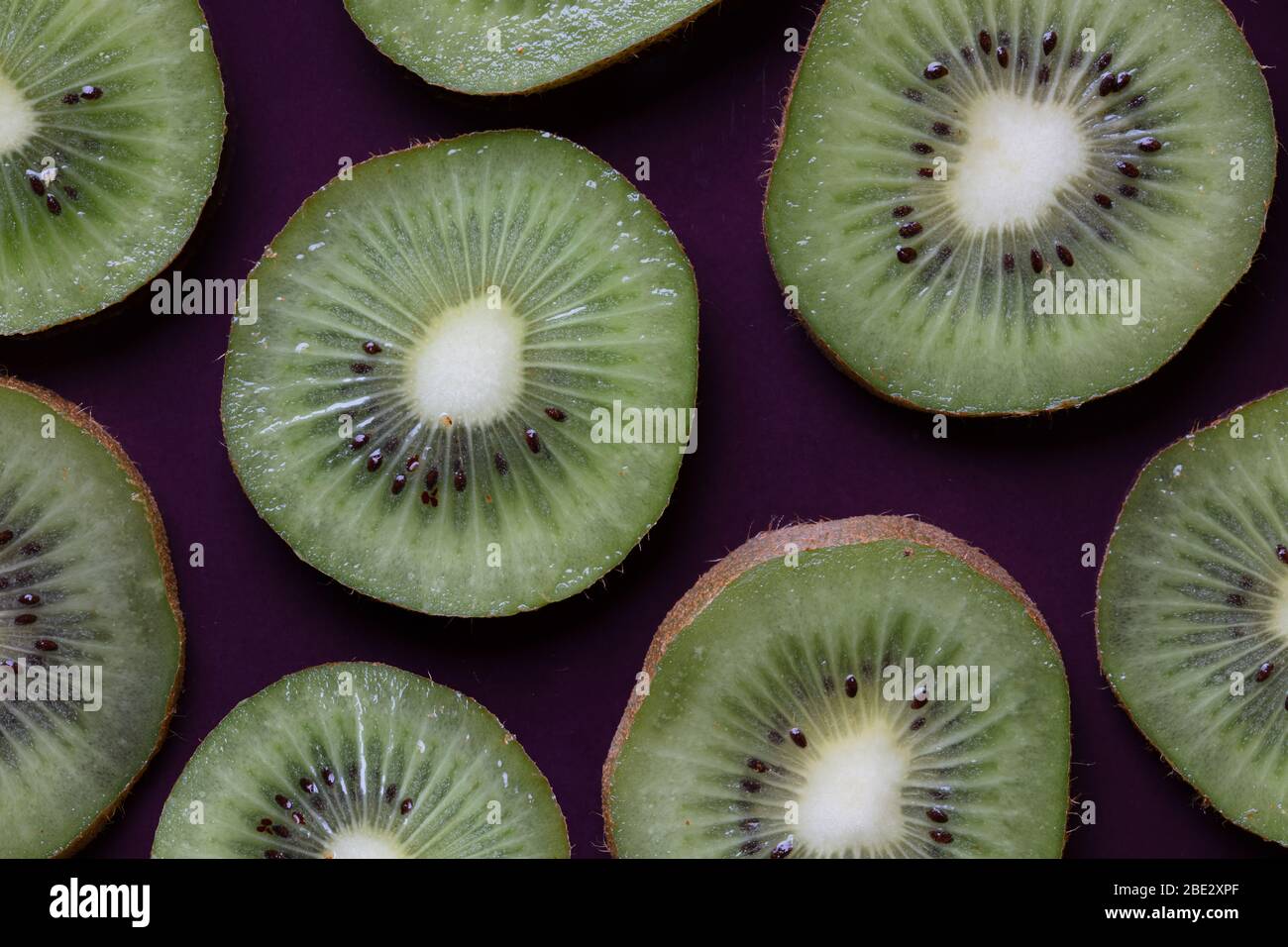 topview ist eine fantastische Fotokomposition aus frischen, leckeren, geschnittenen Kiwi-Früchten auf einem violetten Hintergrund Stockfoto