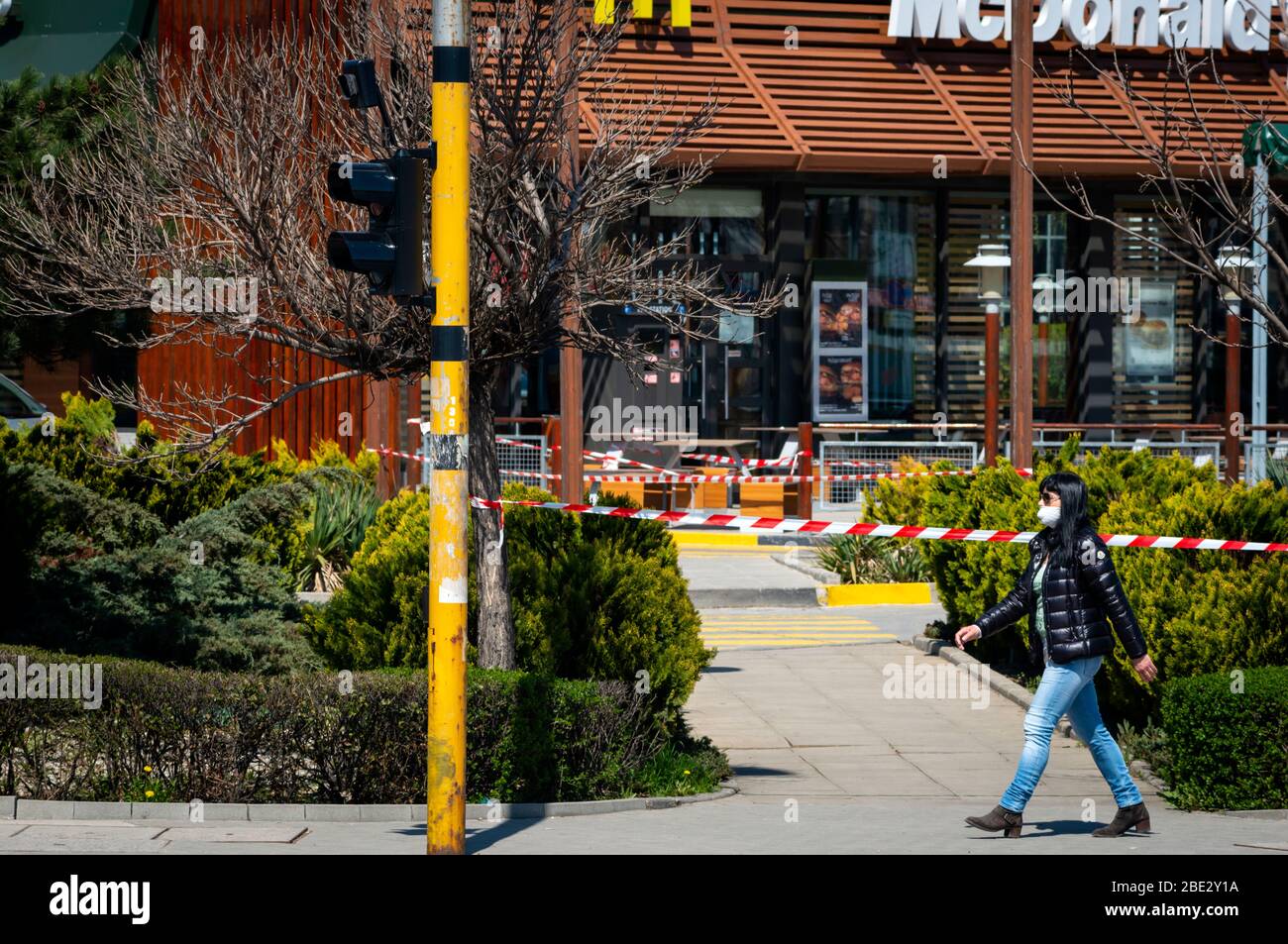 Frau mit Gesichtsschutzmaske geht vorbei an einem geschlossenen für normale Geschäfte McDonald's Fast Food Restaurant, das nur Essen zum Mitnehmen erlaubt aufgrund der Ausbreitung der Coronavirus-Pandemie von Covid-19 in Sofia, Bulgarien seit 2020 Stockfoto