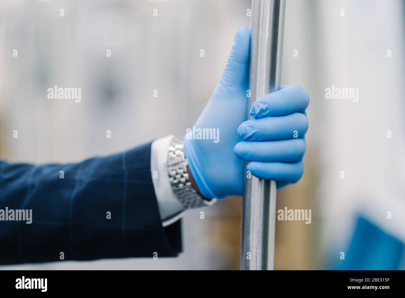 Mans Hand in blauen Einweg-Handschuh berühren Handlauf im öffentlichen Verkehr. Pandemievorsorge. Schutz vor Viren und Bakterien. Coronavirus an Stockfoto
