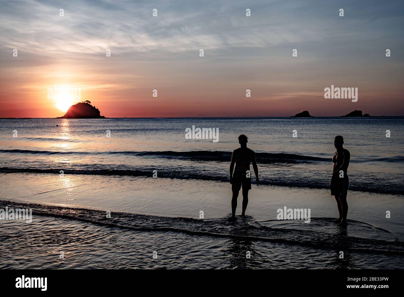 Sonnenuntergang am Strand von Nacpan mit zwei Personen, die für ein Bad bereit sind Stockfoto