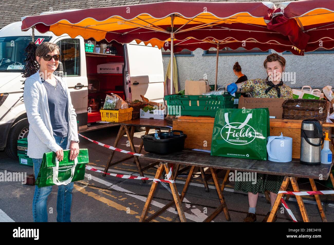 Skibbereen, West Cork, Irland. April 2020. Eine Gruppe lokaler Produzenten hat sich zusammengeschlossen, um Lebensmittelkästchen Sammlungen zu organisieren. Der Kunde, der als „Nachbar Food“ bezeichnet wird, durchsucht die Website und gibt auf und bezahlt seine Bestellung. Der Kunde erhält dann eine Abholzeit, die den ganzen Tag über gestaffelt wird, um die Richtlinien der Regierung zur sozialen Distanzierung einzuhalten. Der Kunde nimmt dann seine Bestellung ab, ohne Geld überreichen zu müssen. Ihre Bestellung von Emma Mock nahm die Kundin Ann Hillyard aus Baltimore ab. Kredit: Andy Gibson/Alamy Live News. Stockfoto