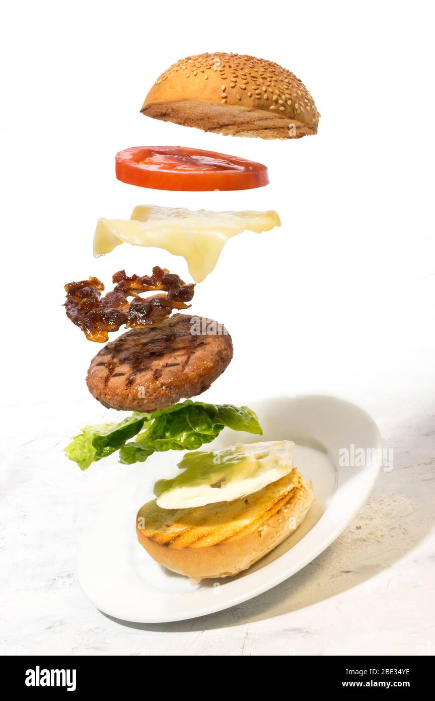 Burger Zubereitung geschnittene Zutaten schweben auf weißem Hintergrund Stockfoto