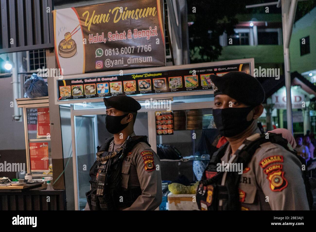 11. April 2020, Lhokseumawe, Aceh, Indonesien: Polizei steht Wache während eines gemeinsamen indonesischen Polizei- und Militärteams mit der Regierung patrouilliert in einem überfüllten Café, ohne soziale Distanz zu nutzen, inmitten der Angst vor dem COVID-19 Coronavirus in Lhokseumawe, Provinz Aceh. Die Regierung Lhokseumawe sanktionierte und widerrief die Lizenzen einiger Coffee Shops, die gegen die lokalen Regierungsvorschriften verstoßen, weil sie den Kunden keine soziale Distanzierung auferlegen, wurden lokale Vorschriften angewendet, um die Verbreitung des Coronavirus zu verhindern. Die indonesische Regierung hat auch staatliche Vorschriften für große s erlassen Stockfoto