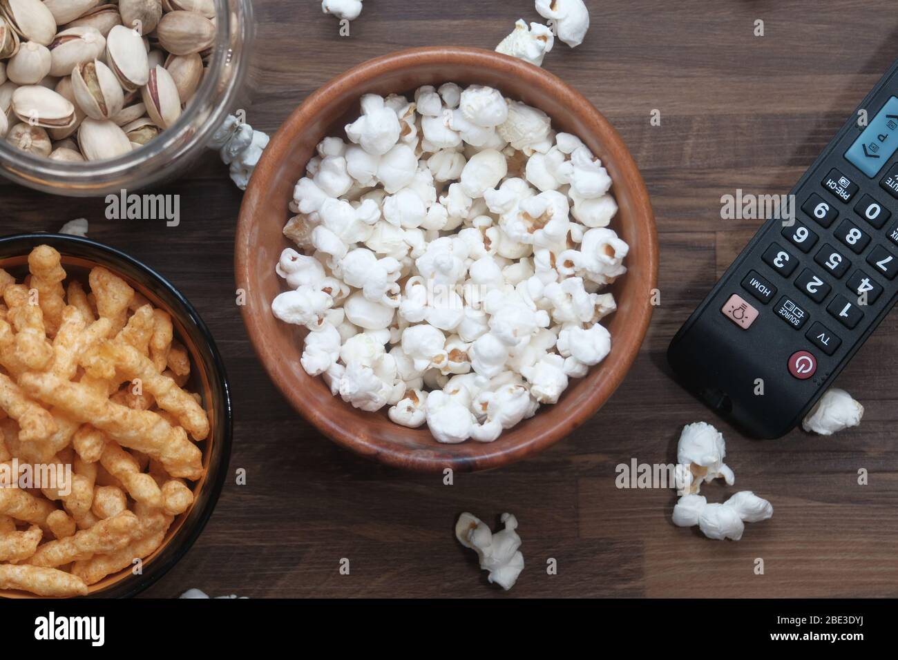 Eine Schüssel Popcornchips, Nuss und TV-Fernbedienung, Stockfoto