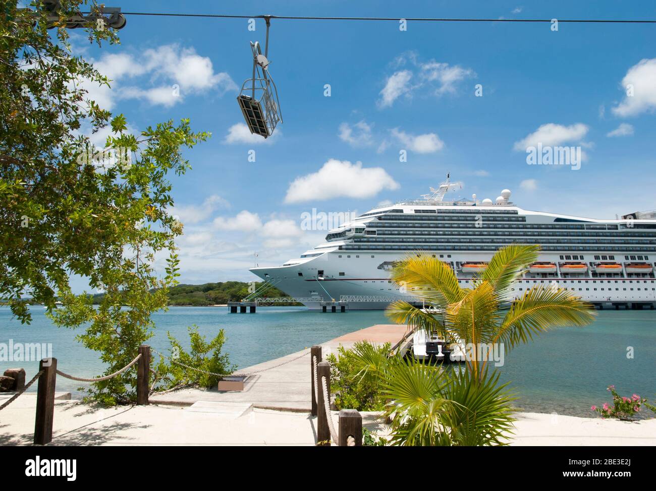 Der Blick auf das vertäute Kreuzfahrtschiff und eine Seilbahn, die Touristen zum Strand der Mahogany Bay auf der Insel Roatan (Honduras) bringt. Stockfoto