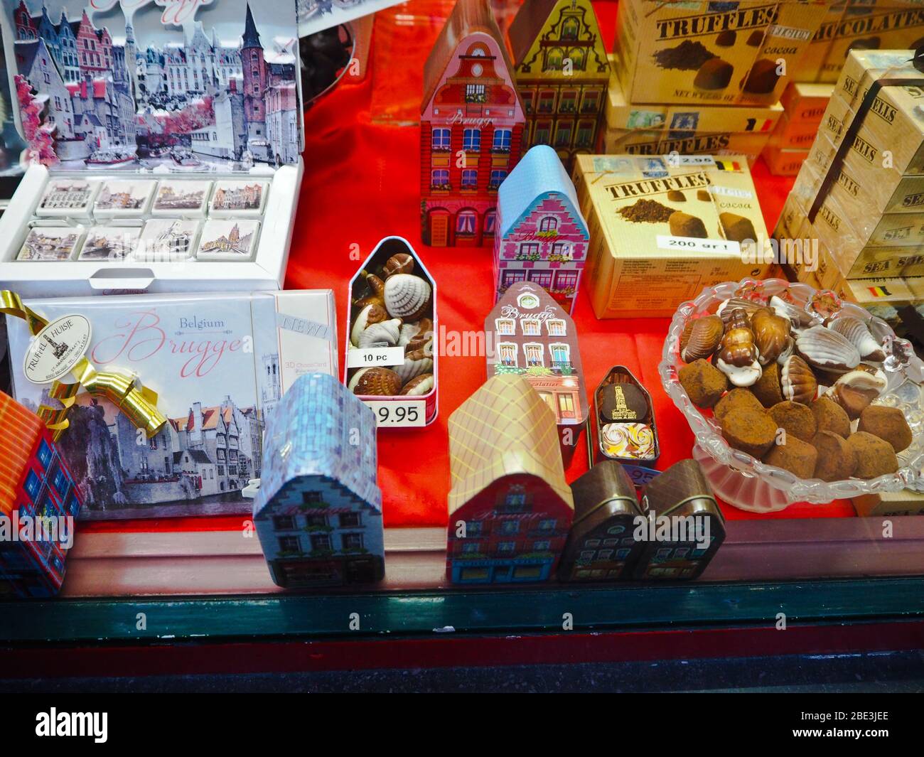 Fenster eines Schokoladenladens, in dem Trüffel, Pralinen, Statuen und andere Schokoladenartikel in Brügge, Belgien, verkauft werden Stockfoto
