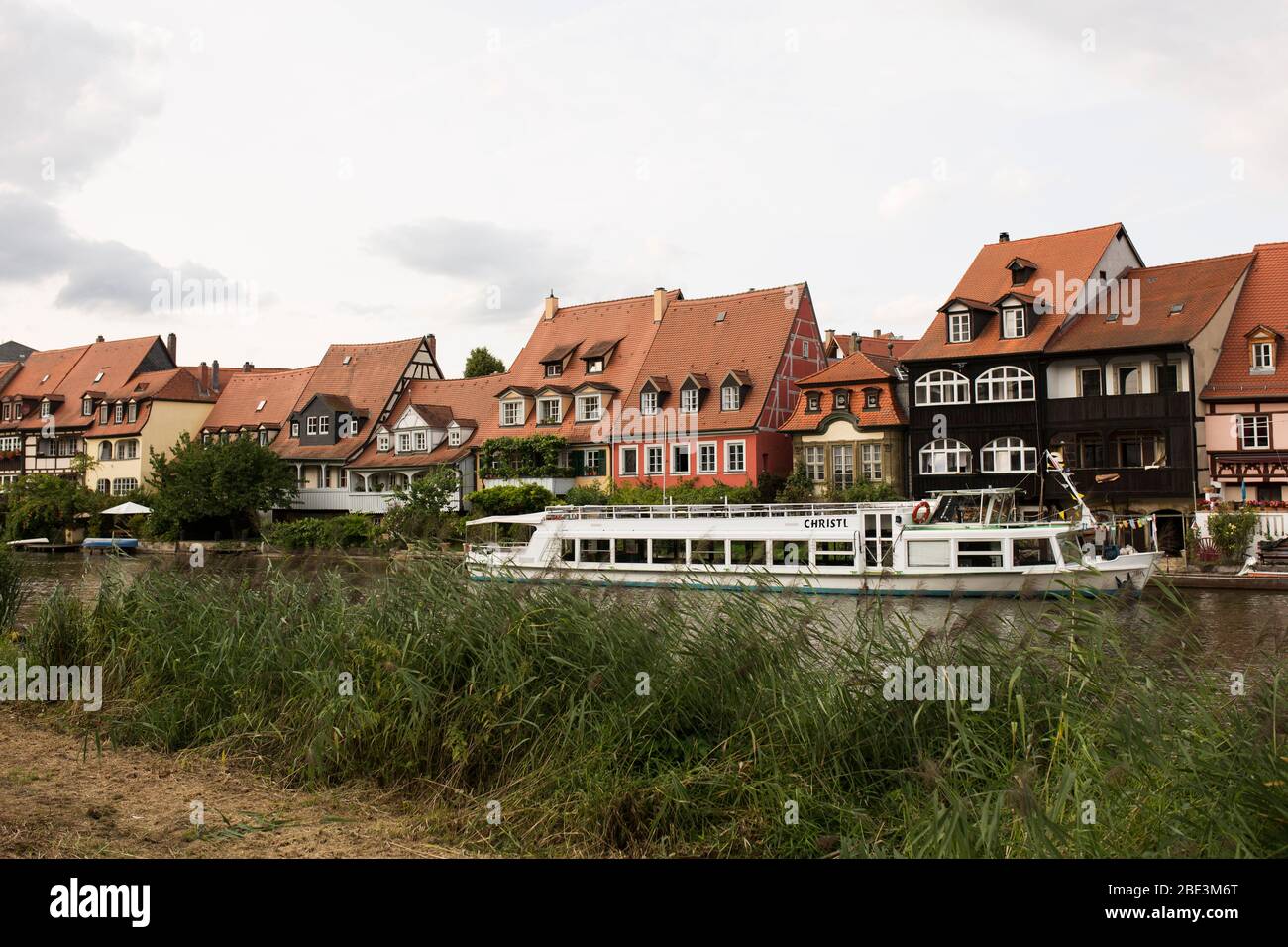 Ein Ausflugsboot und Hausreihe entlang der Regnitz in Bamberg, Oberfranken, Bayern, Deutschland. Stockfoto
