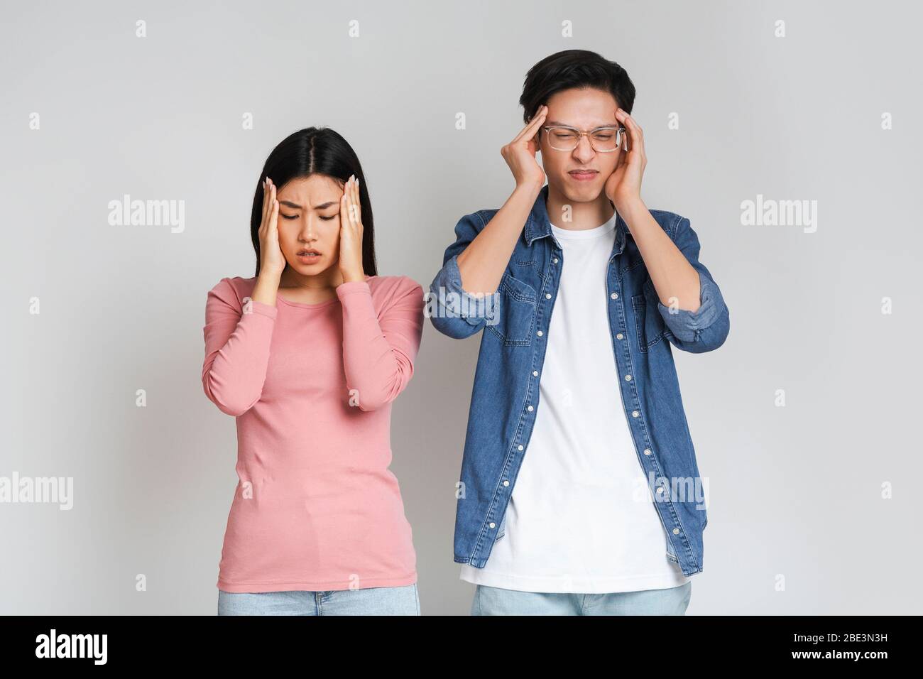 Asiatische traurige Paar mit Kopfschmerzen, berühren ihre Tempel Stockfoto