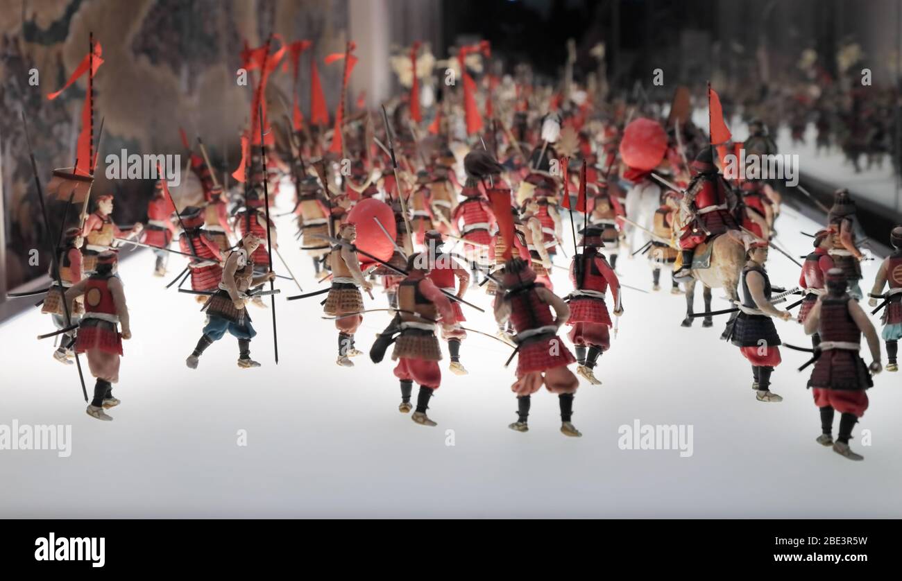 Osaka, Japan - 28 Dec 2019: Spielzeugarmee alter japanischer Krieger mit roten Fahnen, die in eine Schlacht ziehen, wenn historische Rekonstruktion angezeigt wird. Stockfoto