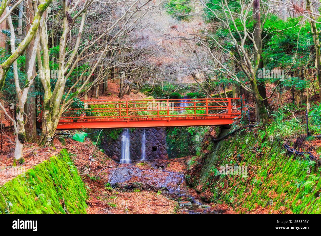 Abgelegener Park in Ohara Dorf hoch in den Bergen rund um Kyoto - Frischwasserstrom unter roter Brücke auf einem Wanderweg. Stockfoto