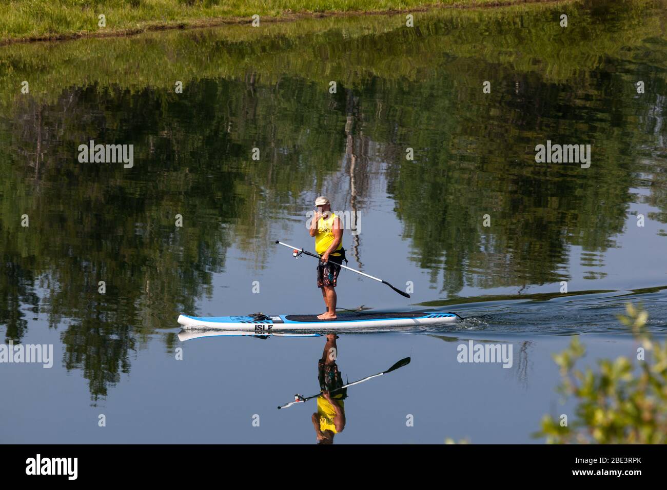 Grand Teton National Park, Wyoming / USA - 17. Juli 2014: Ein Mann, der auf einem Paddelbrett den Snake River hinunter schwimmt und mit seiner Hand ein Schild mit dem "Hang-Ten" gibt Stockfoto