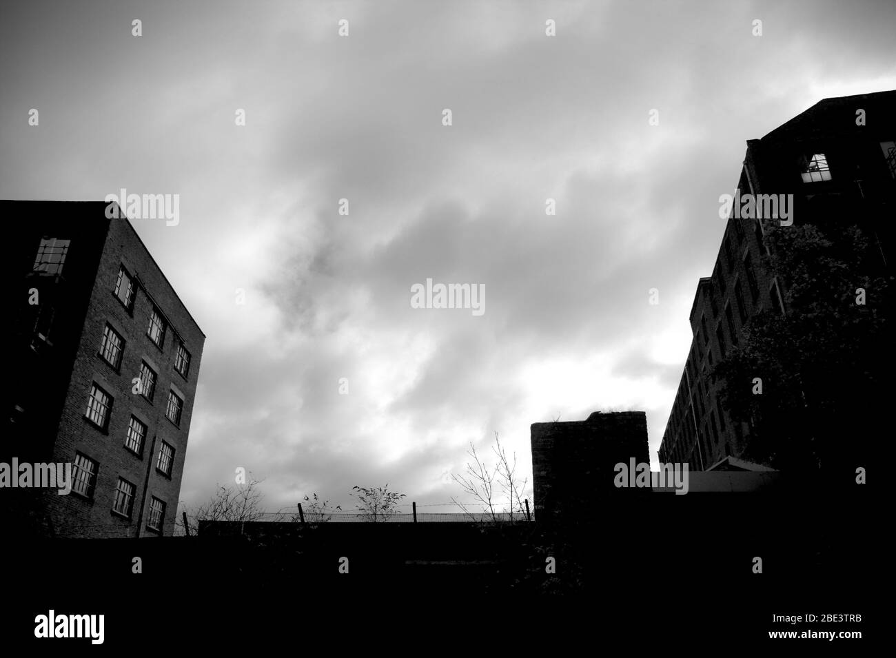 Monochromer Himmel, eingerahmt von zwei verfallenen Mühlen im Stadtteil Ancoats von Manchester Stockfoto