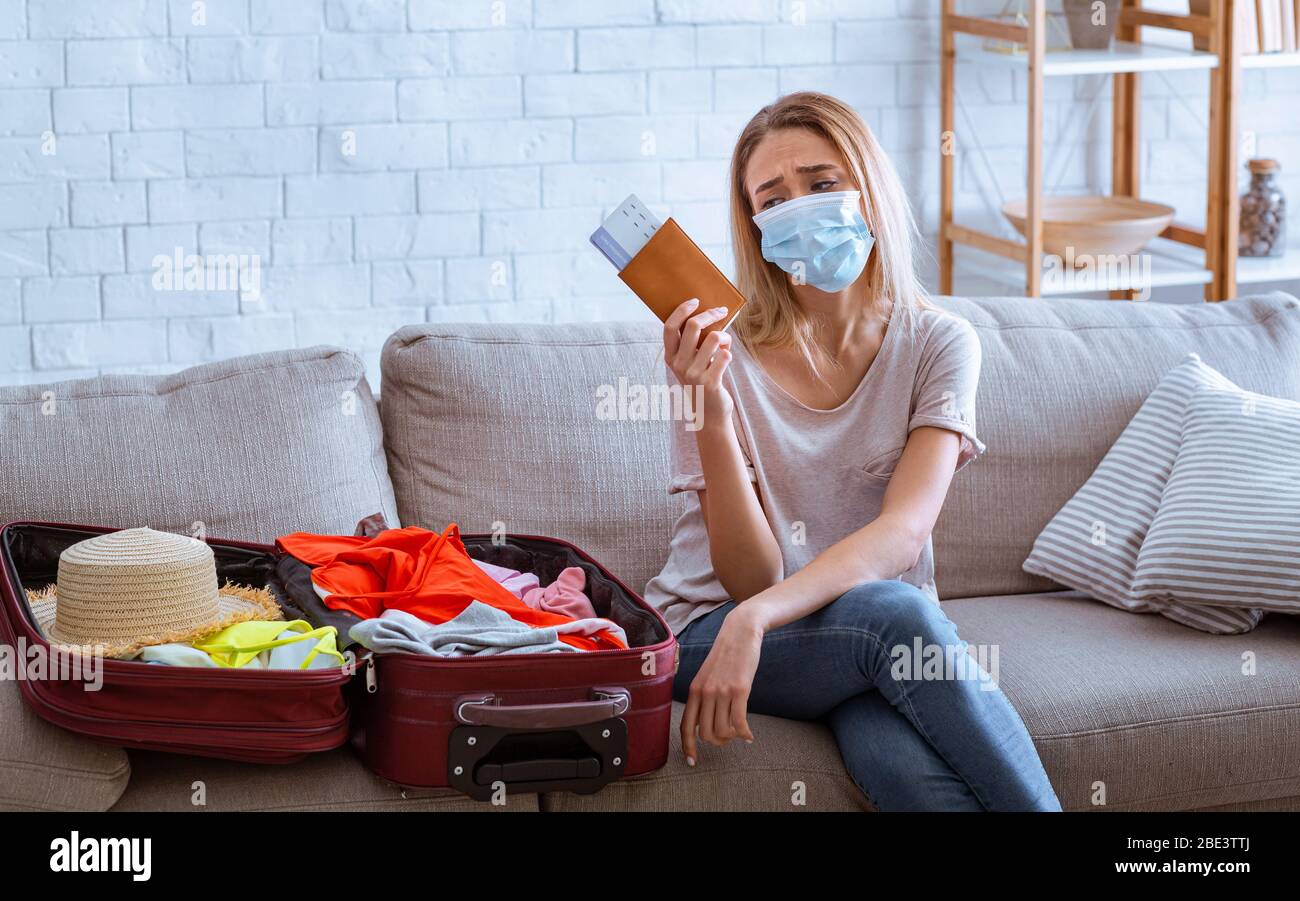 Trauriges Mädchen in Schutzmaske beim Blick auf Tickets Stockfoto