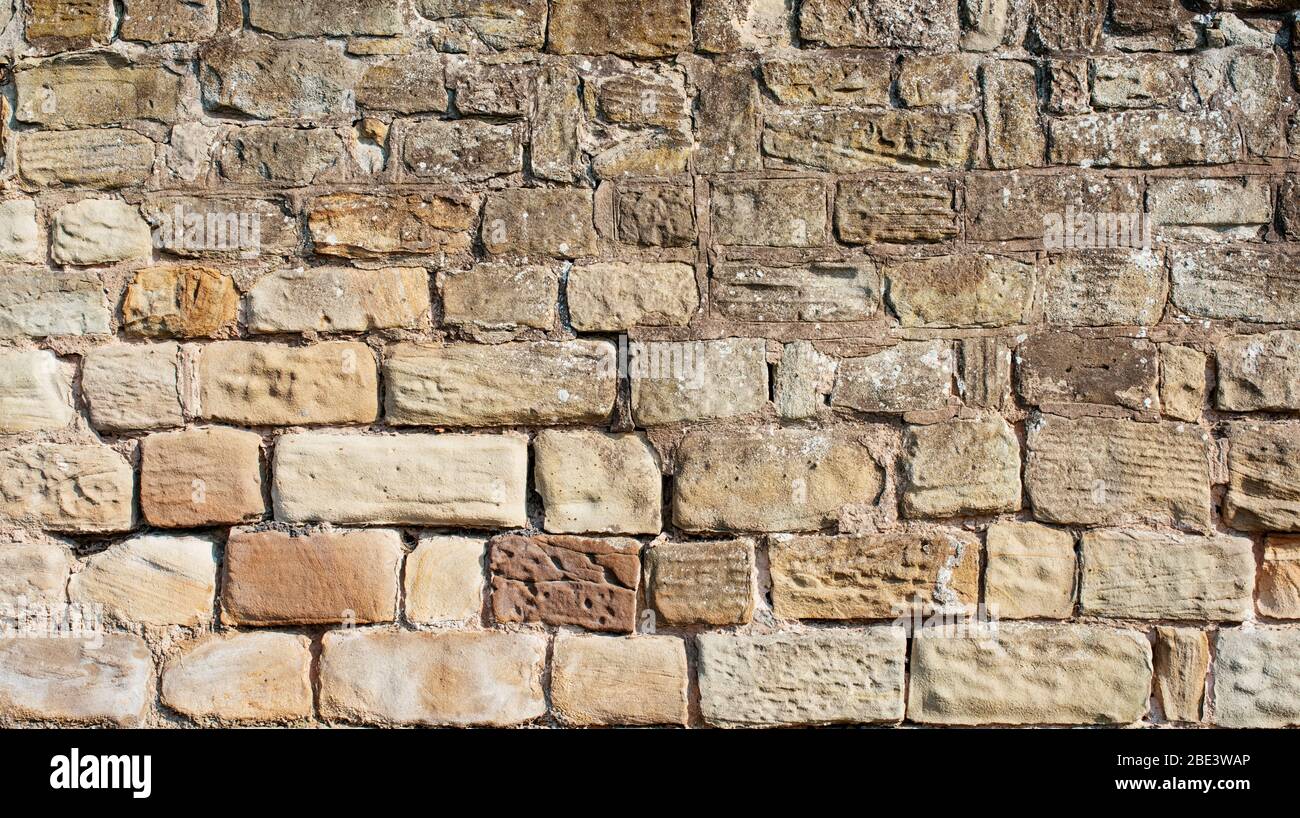 Alte gelbe und braune Sandsteinwand aus Blöcken von unregelmäßiger Form Hintergrund gemacht Stockfoto