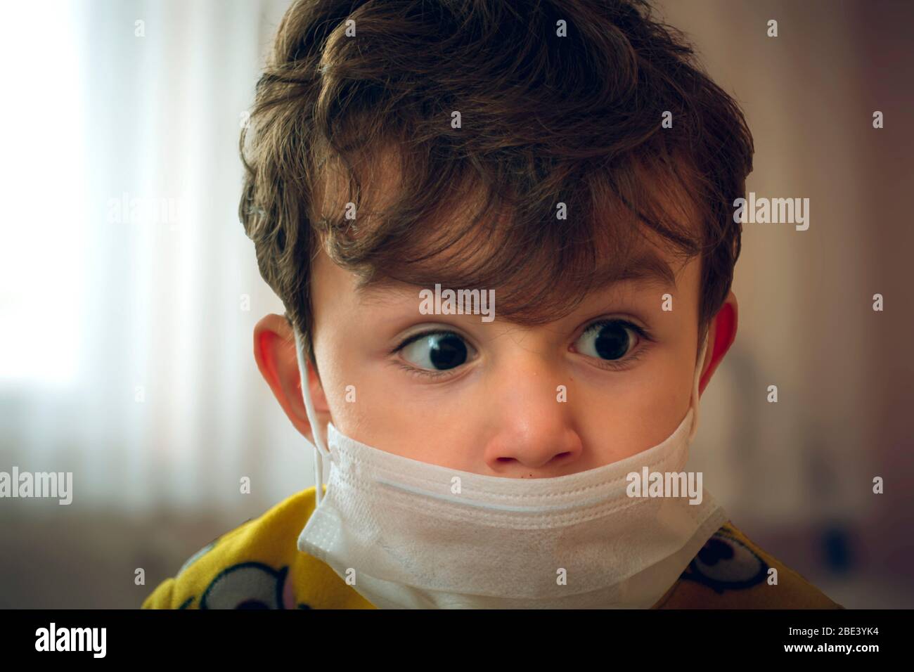 3 Jahre altes türkisches Baby trägt chirurgische Maske und spähtet an einem Punkt ängstlich Stockfoto