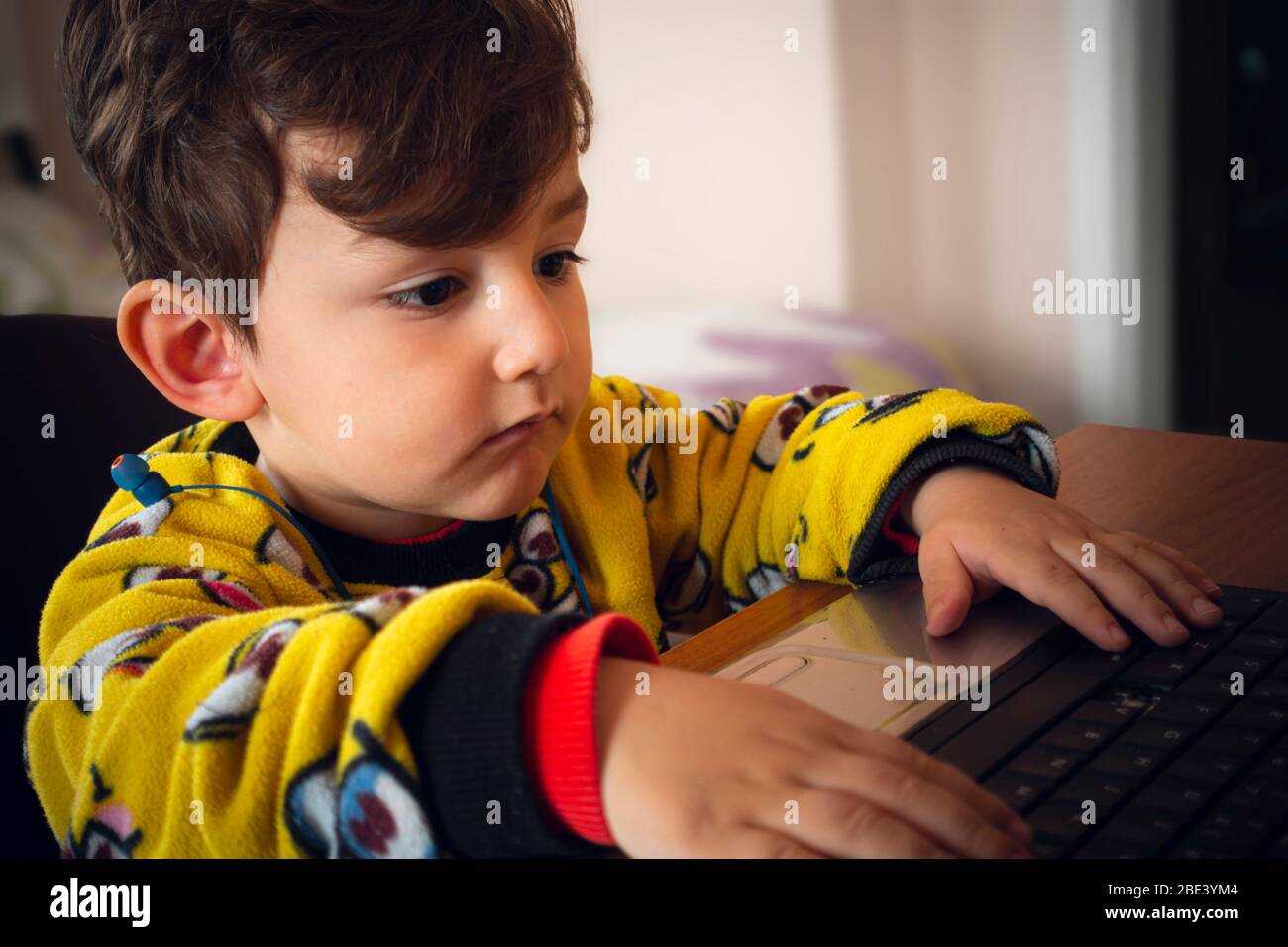 3 Jahre alt neugierig türkischen Baby trägt gelben Pyjamas spielen mit Laptop Stockfoto