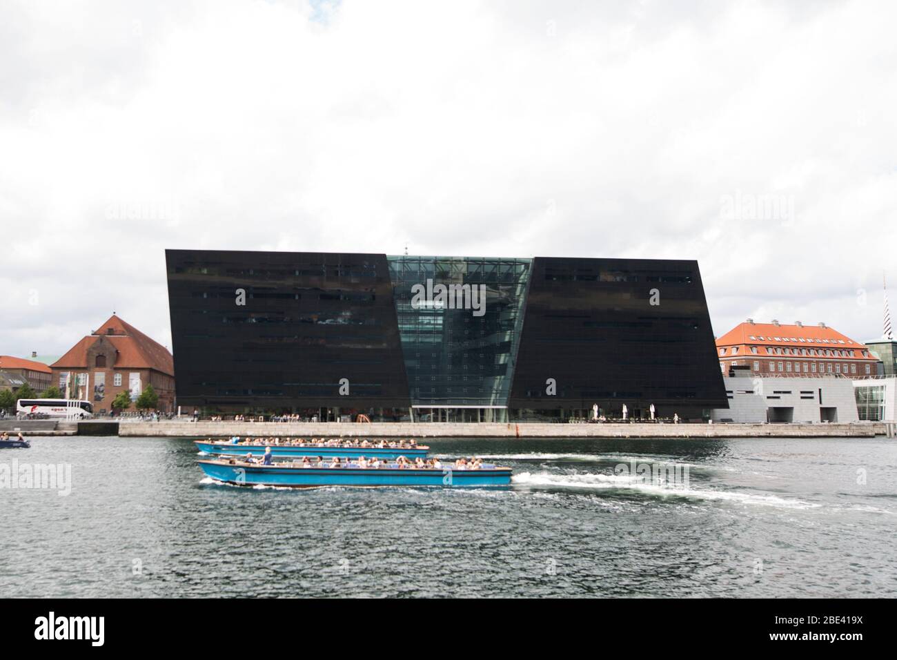 Zwei Boote fahren vor der Königlichen Bibliothek (Kongelige Bibliotek), bekannt als der Schwarze Diamant, im Zentrum von Kopenhagen, Dänemark. Stockfoto