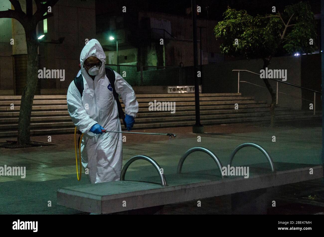 Reinigungspersonal zu Fuß desinfizieren einen Platz und Straßen. Tag der Nacht Reinigung und Desinfektion in den Straßen von Caracas, Venezuela, um die spr Stockfoto