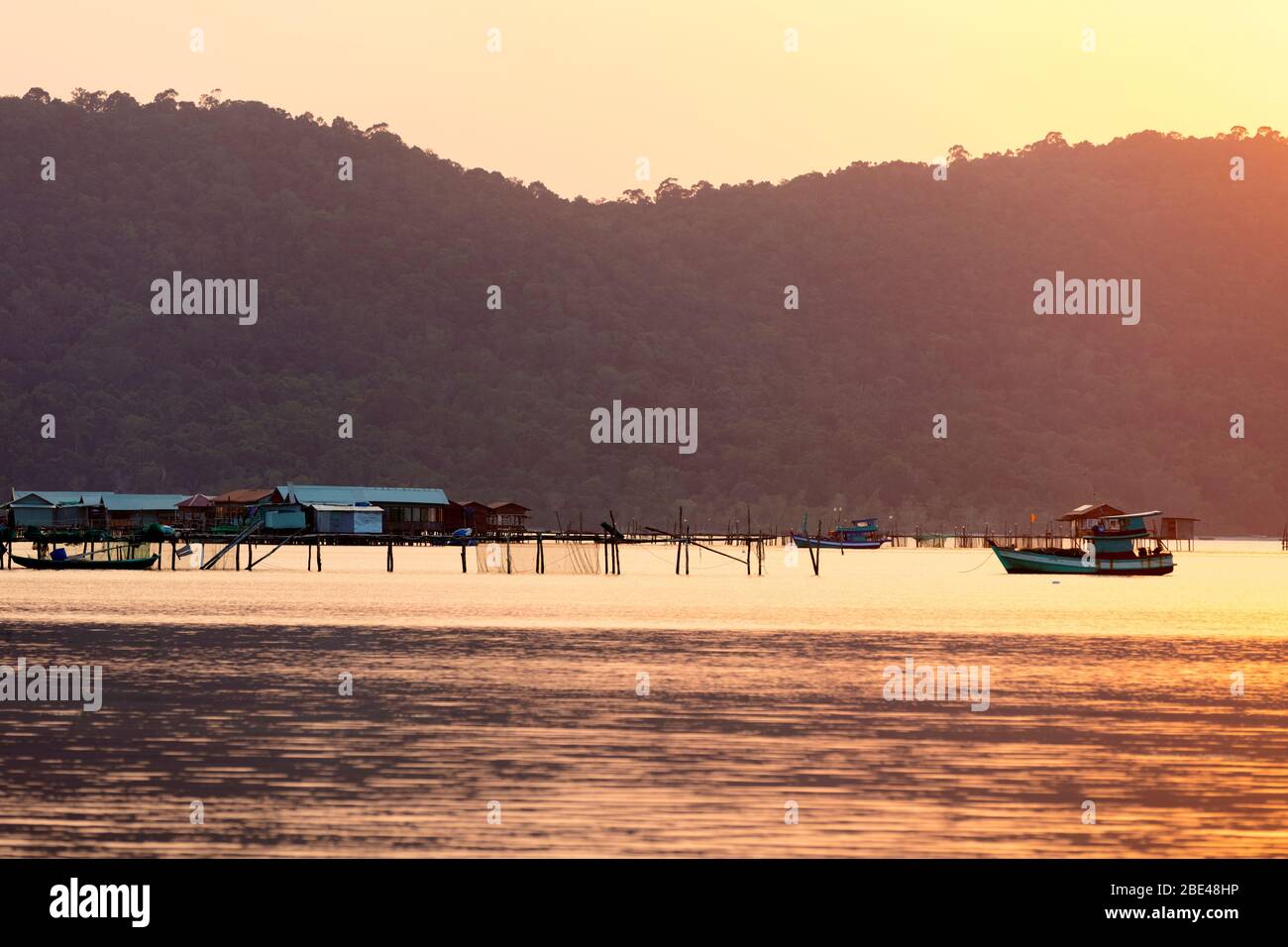 Boote und Gebäude auf dem Wasser während eines glühenden rosa Sonnenuntergang, Starfish Beach; Phu Quoc, Kien Giang Provinz, Vietnam Stockfoto